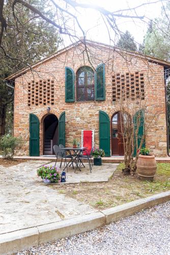 a brick house with green doors and a table and chairs at Borgo Il Poggio Agriturismo in Montaione