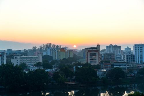 a city skyline with the sunset in the background at Hotel Vila Rica Flat in Resende