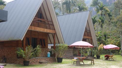 a building with two roofs with tables and umbrellas at Orau Asthana in Arau