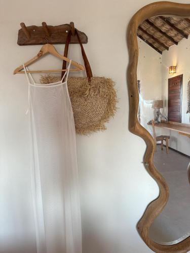 a dress hanging on a wall next to a mirror at Vila Ronquinha - Arpoador in Tutóia