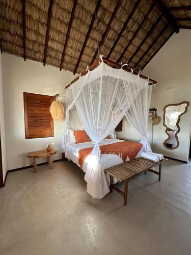 a bedroom with a canopy bed and a bench at Vila Ronquinha - Arpoador in Tutóia