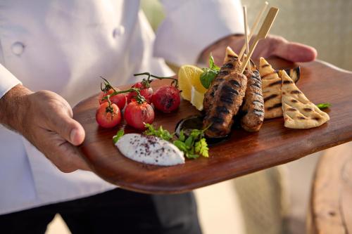 a man holding a plate with food on it at Ikos Dassia in Dassia