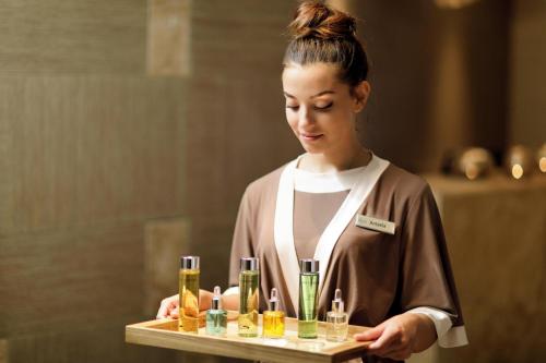 a woman holding a tray with bottles of alcohol at Ikos Dassia in Dassia