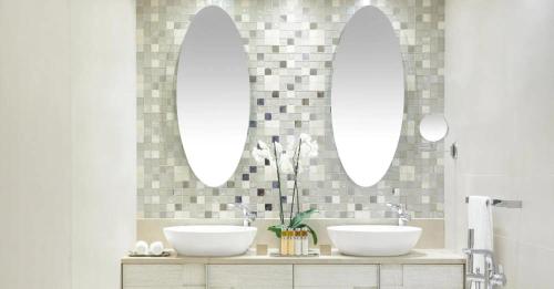 a bathroom with two sinks and two mirrors at Ikos Dassia in Dassia