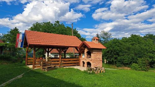 a small building with a red roof in the grass at Kokotova hiža in Gornja Konjšćina