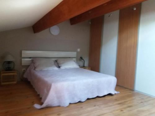 une chambre avec un lit blanc et un parquet dans l'établissement Maison de village dans Languedoc-Roussillon, à Vergèze