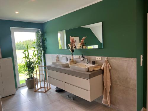a bathroom with three sinks and a green wall at Grünblick Oase No1 Ferienwohnung Wiesmoor in Wiesmoor