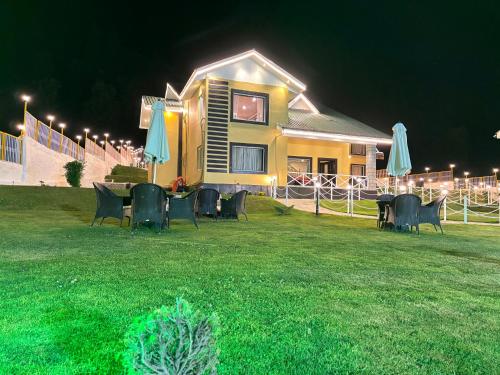 a house with chairs and umbrellas in a yard at night at Arco Hotels & Resorts sonamarg in Sonāmarg