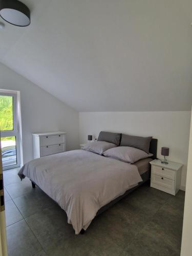 a white bedroom with a large bed and a window at Villa Lago am Plauer See in Alt Schwerin