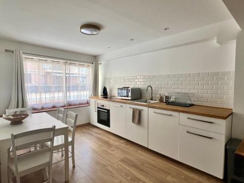 une cuisine avec des armoires blanches et une table et une salle à manger dans l'établissement Charmant T2 Centre ville Bastia, à Bastia