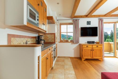 a kitchen with wooden cabinets and a flat screen tv at Weber am Gasteig in Reit im Winkl