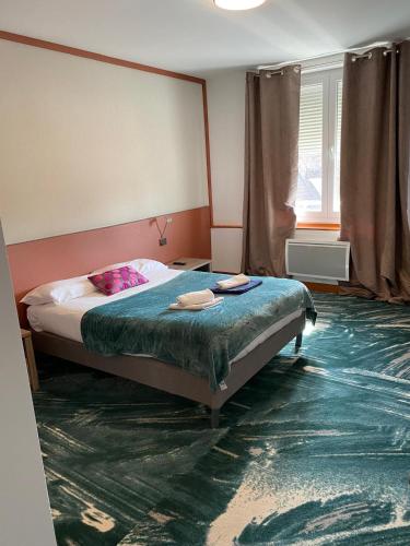 a bedroom with a bed with a green carpet at Hôtel Le Saint Amand in Saint-Amand-Montrond