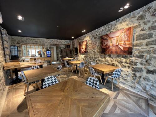 un restaurant avec des tables et des chaises et un mur de pierre dans l'établissement Le 19 - Suite 19 - 50m2 - Centre Historique - Clim, à Langeac