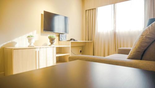 a hotel room with a tv and a chair and a table at Beach Class Convention - Flats em Boa Viagem por Yolo in Recife