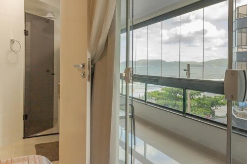 a room with a window with a view of the ocean at Apto em condomínio Pé na Areia em Itapema N1672 in Itapema