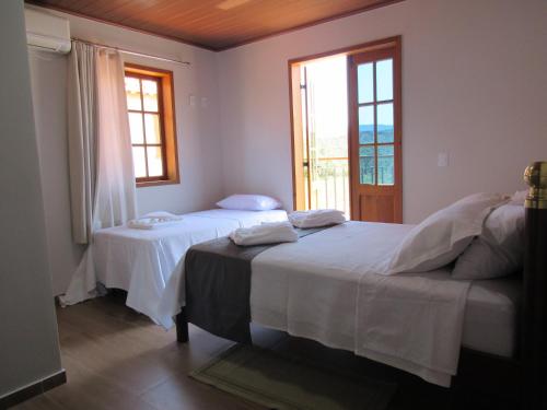 two beds in a room with two windows at Casa 1 Chalé Alto dos Bandeirantes in Tiradentes