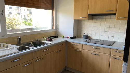 une cuisine avec des armoires en bois, un évier et une fenêtre dans l'établissement cosy quiet, à Rueil-Malmaison
