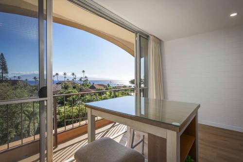 a dining room with a glass table and a balcony at Aston Maui Kaanapali Villas in Lahaina