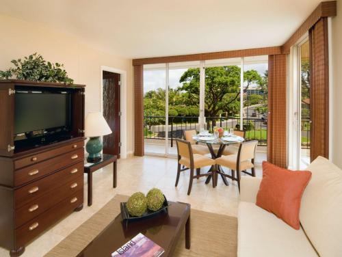 a living room with a television and a table with chairs at Aston Maui Kaanapali Villas in Lahaina