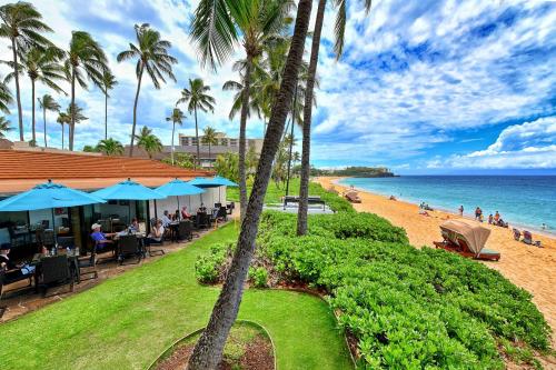 a restaurant on the beach with palm trees and the ocean at Aston Maui Kaanapali Villas in Lahaina