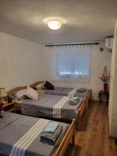 ein Zimmer mit drei Betten und einem Fenster in der Unterkunft Apartment Anis in Mostar