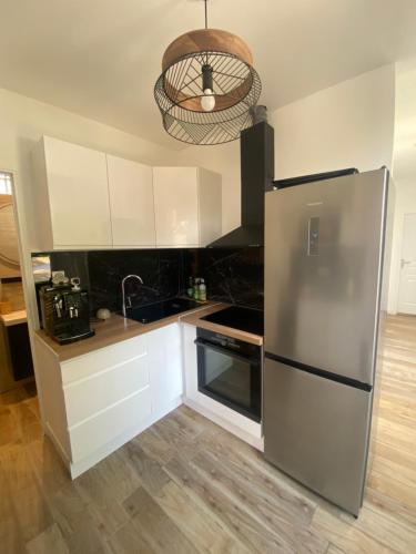 une cuisine avec un réfrigérateur en acier inoxydable et des armoires blanches dans l'établissement Chambres rénovées proches de Paris Centre, des sites olympiques, avec belle terrasse calme, à Argenteuil
