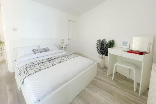 a white bedroom with a bed and a desk at Rodney Road in Great Yarmouth