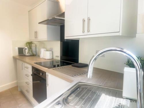 a kitchen with white cabinets and a sink at Rodney Road in Great Yarmouth