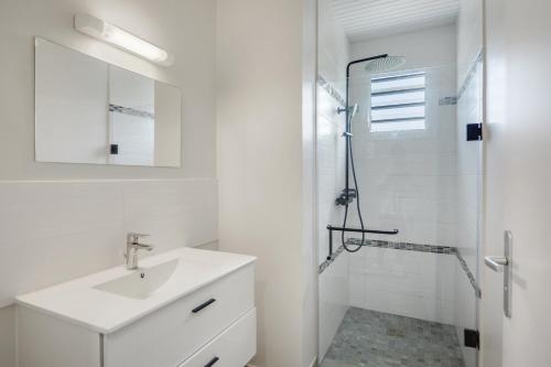a white bathroom with a sink and a shower at Villa Cherry in Le Diamant