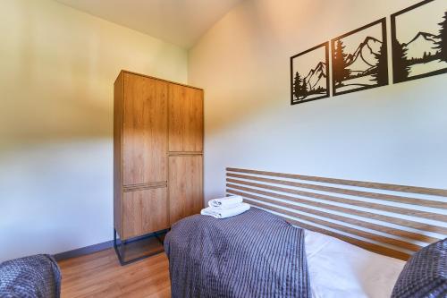 a bedroom with a bed and a wooden cabinet at LAGUNA Loftowy na Wzgórzu in Polanica-Zdrój