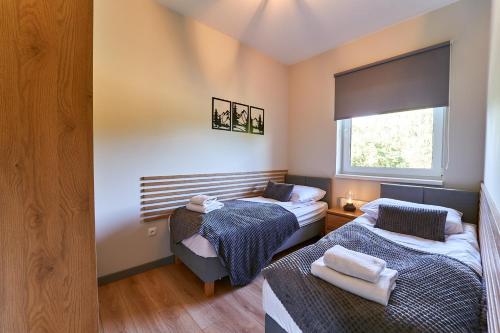 two beds in a room with a window at LAGUNA Loftowy na Wzgórzu in Polanica-Zdrój