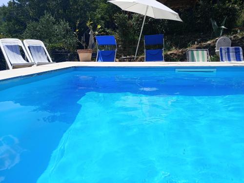 a swimming pool with chairs and an umbrella at Il Podere di Massi in Barberino di Mugello