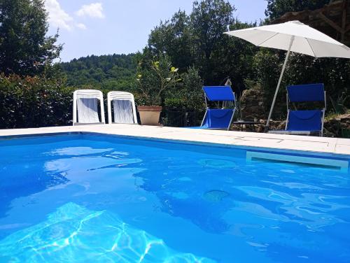 a swimming pool with two chairs and an umbrella at Il Podere di Massi in Barberino di Mugello