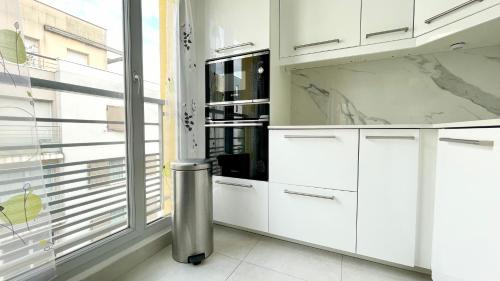 une cuisine avec des placards blancs et une grande fenêtre dans l'établissement Charmant Appartement Cosy pour 4, à Pantin