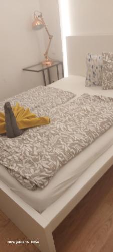 a white bed with a yellow blanket on it at Miracle apartman in Szigethalom