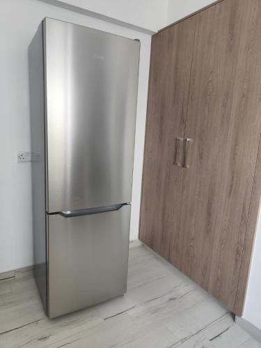 a stainless steel refrigerator next to a wooden door at Marina view seaside apartment in Larnaka