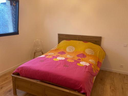 - un lit avec une couette rose et jaune dans l'établissement Maison plain-pied - Guidel, à Guidel