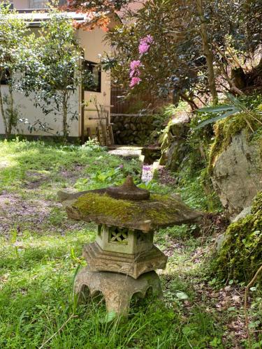 a stone birdbath in the grass in a garden at 高野山 こころの寺子屋リトリートハウス -Koyasan Retreat House IKKOSHO in Koyasan