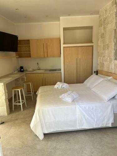 a bedroom with a large white bed and a kitchen at Luna D'Argento in Leporano Marina