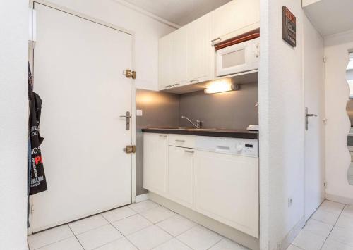 une cuisine avec des placards blancs et des appareils électroménagers blancs dans l'établissement Bel appartement avec terrasse, au Cap d'Agde