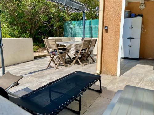 un patio avec une table, des chaises et un parasol dans l'établissement Bel appartement avec terrasse, au Cap d'Agde