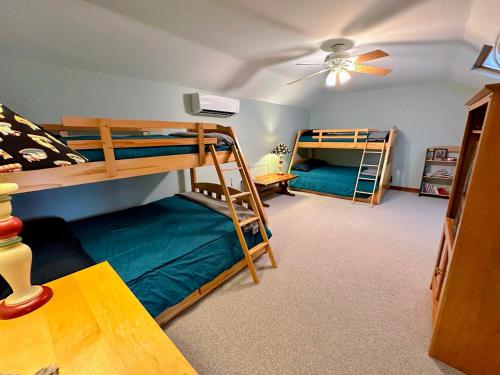 a bedroom with two bunk beds and a ceiling fan at Bretton Woods home steps from the slopes, AC, pool passes, discounted cog tix! in Bretton Woods