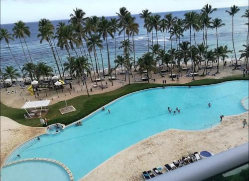 a large swimming pool with palm trees and the ocean at Beachfront Apartment with Jacuzzi in Juan Pedro