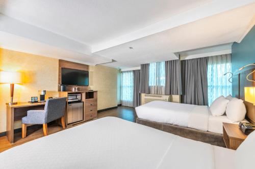 a hotel room with two beds and a desk at Grand Park Hotel & Suites Downtown Vancouver, an Ascend Collection Hotel in Vancouver