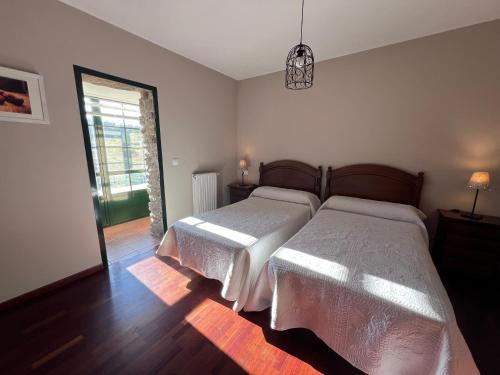 a bedroom with two beds and a large window at Fogar dos Antigos in Mazaricos