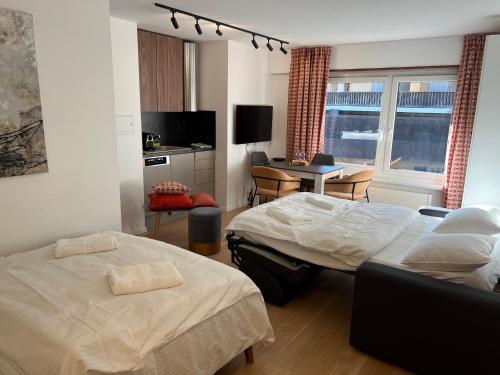 a bedroom with two beds and a table and a desk at La Perle Montana in Crans-Montana