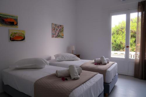 two beds in a white room with a window at Grand Bleu Apartments & Villas in Ermioni