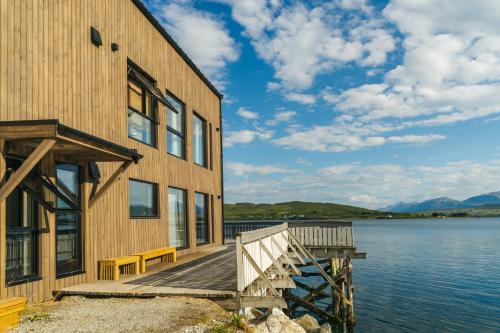 a building with a wooden dock next to the water at Steam Pier Adventure Hotel in Kvaløya