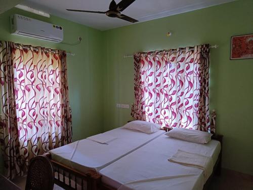 a small bedroom with a bed and two windows at SEVENSTAR RESIDENCY in Varkala