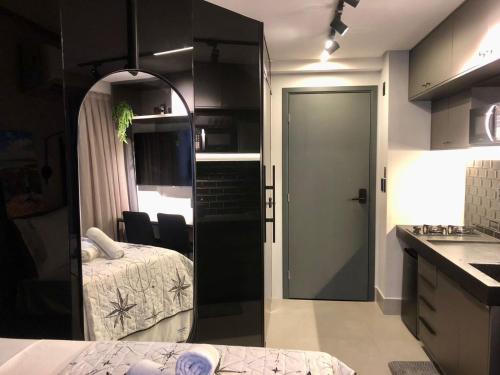 a bedroom with a bed and a door to a kitchen at Get By Side - Jardim Oceania in Tambaú